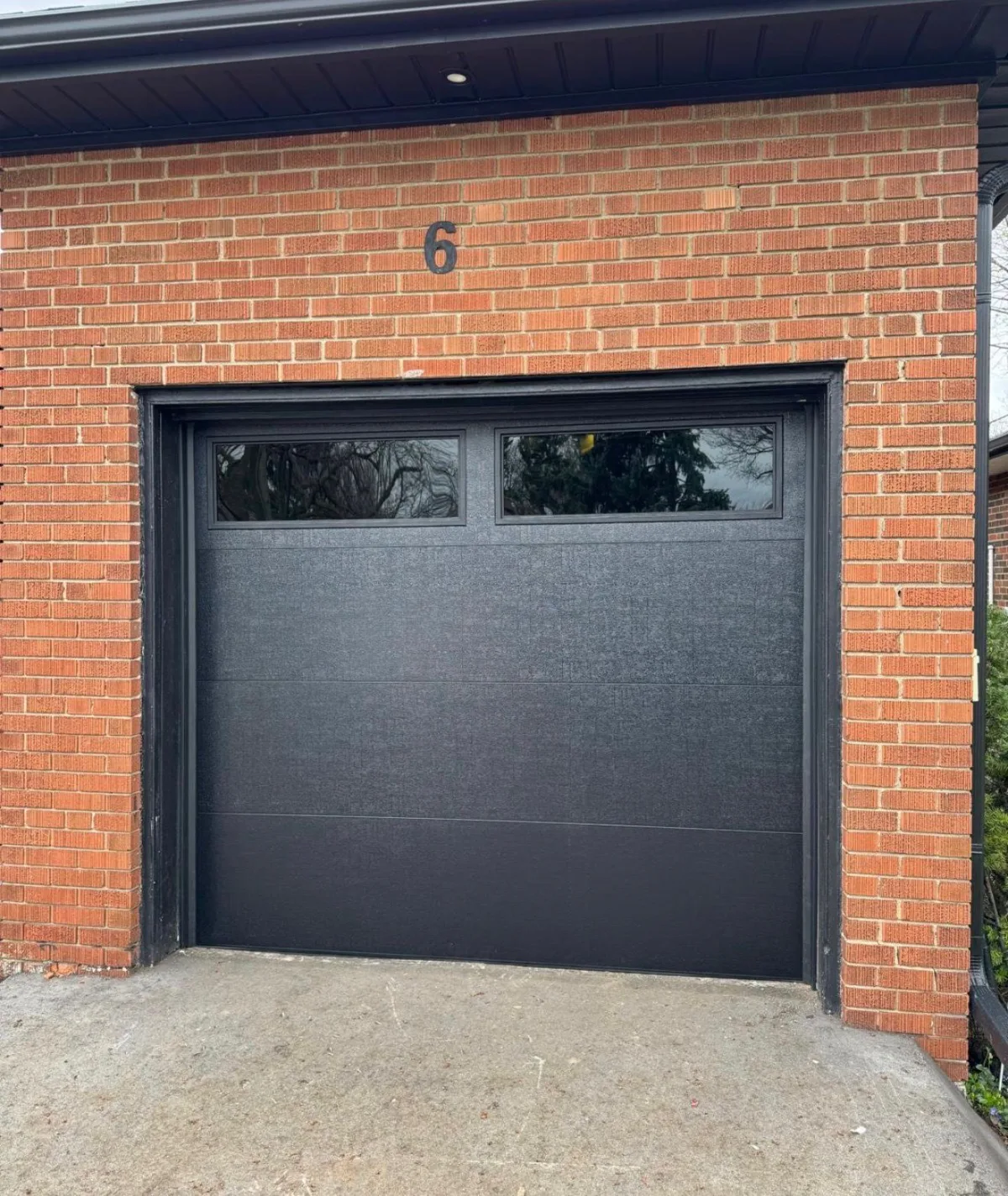 Black garage door on red brick home